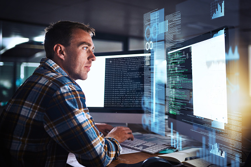 Shot of a young programmer working at his computer with an overlay of computer graphics